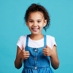 Image showing Happy, thumbs up and portrait of a child in a studio with success, happiness and achievement. Smile, positive and face of a girl kid with a satisfaction or approval hand gesture by a blue background.