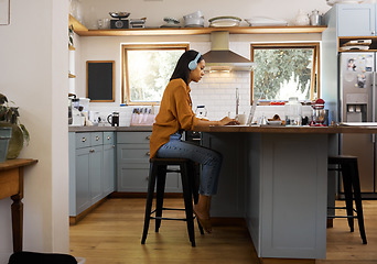 Image showing Home, remote work and business woman on laptop for research project, strategy and planning in kitchen. Freelancer, focus and girl with headphones for music working online, busy and typing on computer