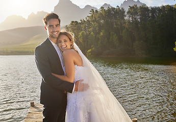 Image showing Happy, hug and portrait of a married couple by a lake for a ceremony, celebration and marriage. Smile, affection and a bride and groom hugging after wedding and relationship commitment in nature