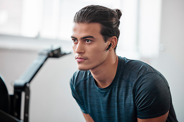 Image showing Man, fitness and serious in gym, earpods and listen to music for motivation to exercise with training and wellness. Health, active lifestyle and young male with radio streaming, wifi and workout