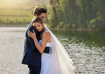 Image showing Wedding couple, hug and relax by lake for love on romantic getaway or honeymoon in nature. Calm woman hugging man in happy marriage relaxing by the water together enjoying the loving embrace outdoors