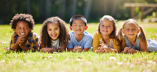 Image showing Portrait, diversity and children on grass, friends and summer break with smile, chilling and relax. Face, kids and young group in park, multiracial and fun on vacation, weekend and joyful together