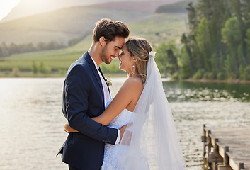 Image showing Happy wedding couple, hug and love by lake for romantic honeymoon getaway in nature. Man and woman hugging touching foreheads in happiness for marriage relationship or loving embrace in the outdoors