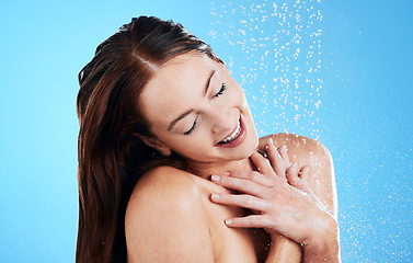 Image showing Shower, water and happy woman in studio, blue background and cleaning for hygiene. Female model washing with wet drops for beauty, skincare and grooming for self care, happiness and wellness routine