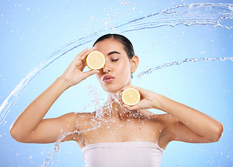 Image showing Beauty, water splash and lemon with woman in studio for natural cosmetics, nutrition and detox. Glow, fruits and hydration with female and pouting on blue background for vitamin c, face and skincare