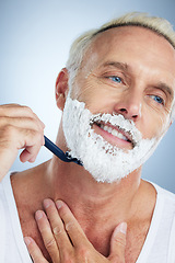 Image showing Senior man, face and razor shaving beard with cream for grooming, skincare or hair removal against a studio background. Happy mature male with shaver, creme or foam for hygiene or facial treatment