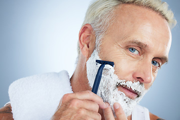 Image showing Senior man, face and razor for shaving, skincare or grooming beard and hair removal against a studio background. Portrait of mature male with shaver, cream or foam cosmetics for facial treatment