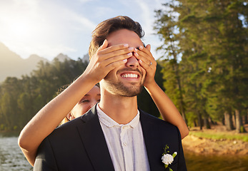 Image showing Love, wedding or surprise with a bride and groom by a lake, in celebration of a ceremony of tradition. Romance, marriage and hands over face with a married couple playing or joking together outdoor