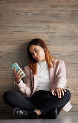 Image showing Young business woman, floor and texting with bored face on social media, app or phone in modern office. Professional female, smartphone and tired with search for email, chat or communication on break