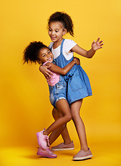 Image showing Children, hug and happy sisters in studio dancing with love, care and support of family on yellow background. Cute young girl kids play together for happiness, fun and positive attitude or fashion