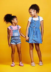 Image showing Children, holding hands and happy sisters in studio with love, care and support of family on yellow background. Cute young girl kids or friends together for happiness, positive attitude or trust