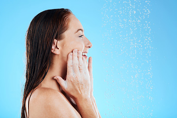 Image showing Shower, water and happy woman with soap on face in studio, blue background and skincare cleaning. Female model washing facial with foam, wet drops and beauty of self care, glow and smile on backdrop