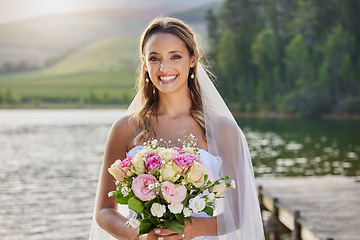 Image showing Portrait, happy bride and bouquet at lake, nature and celebration of commitment, union and marriage. Woman, smile and outdoor wedding of flowers, bridal fashion and excited to celebrate beautiful day