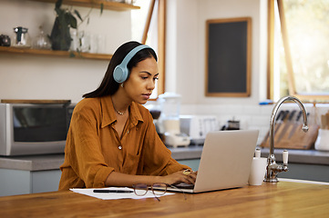 Image showing Home, remote work and business woman on laptop for online project, strategy and planning in kitchen. Freelancer, computer and girl focus with headphones for music, working online and streaming audio