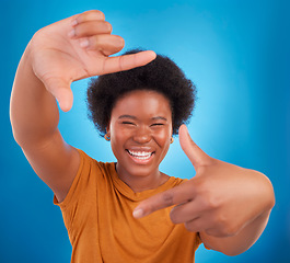 Image showing Finger framing, portrait and happy black woman on blue background, studio and backdrop. Face, female and hands frame perspective, pose and smile of happiness, photography or capture profile picture