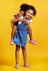 Image showing Children, portrait and happy sisters for piggyback fun in studio with love of family on yellow background. Cute young girl kids or friends smile together for happiness, play and support or care