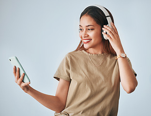 Image showing Woman, music headphones and phone in studio while happy, excited and positive. Female model on white background with smartphone for internet connection or subscription listening to audio or radio