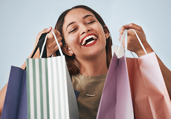 Image showing Shopping bag, portrait and happy woman isolated on studio background wealth, financial freedom or sales promotion. Retail, fashion and excited face of model, person or customer with paper bags offer
