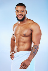 Image showing Black man portrait, muscle body and towel in studio with happiness from bodybuilder fitness. Cleaning, skincare and wellness after sport workout and exercise with isolated, smile and blue background