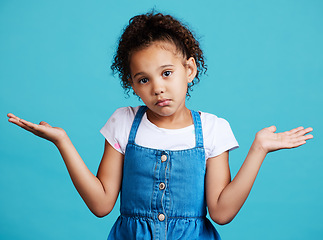 Image showing Portrait, children and shrug with a girl on a blue background in studio feeling confused or lost. Kids, question and doubt with a young female child shrugging her shoulders to gesture whatever
