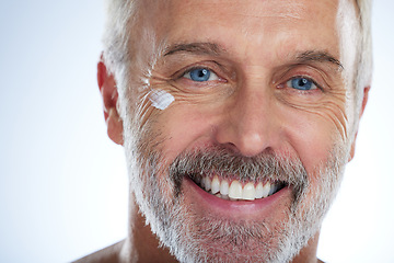 Image showing Old man, cream and smile, eye and wrinkle with skincare, face and beauty, hygiene and grooming on studio background. Portrait, moisturizer and dermatology, anti aging cosmetics and male closeup