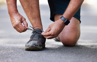 Image showing Hands, shoes and running with a senior man tying his laces outdoor on a road during a cardio workout. Fitness, exercise or footwear with a male runner getting ready for endurance training on a street