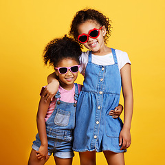 Image showing Children, sunglasses and happy sisters in studio hug for love, care and support of family on yellow background. Cute young girl kids portrait together for happiness, carefree and fashion with a smile