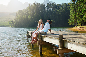 Image showing Young couple, lake and jetty with laughing, happiness and bonding with love in nature for holiday. Man, woman and comic joke on bridge by water to relax with conversation, care and vacation in summer