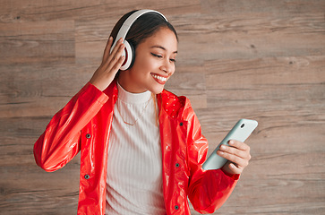 Image showing Phone, headphones and happy woman with music isolated on wood background, audio streaming and mobile app. Gen z student or biracial person listening on cellphone, electronics sound and technology