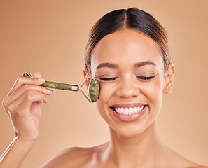 Image showing Happy woman, beauty or face massage with roller, facial product for healthy skincare on studio background. Smile, crystal stone treatment or girl model with dermatology cosmetics or jade marketing