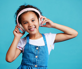 Image showing Music, portrait and girl child with headphones in studio for streaming, subscription and audio on blue background. Face, autism and autistic kid happy with noise canceling headphone while isolated