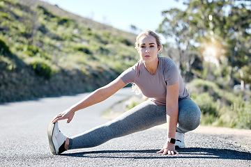 Image showing Fitness, woman and stretching legs on road for exercise, start or workout in nature. Serious, determined and fit sporty female in warm up leg stretch getting ready for training or running outdoors