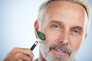 Image showing Senior man, jade roller and portrait for skincare with smile, self care and wellness in studio by white background. Elderly man, facial massage and beauty with stone product, face and dermatology