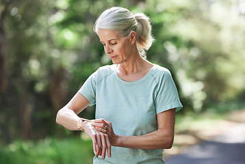 Image showing Senior woman, watch and outdoor for exercise time on run, workout and training on road for fitness. Elderly female person check cardio progress for health and wellness while running in nature