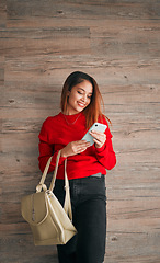 Image showing Phone, fashion and a woman in studio on a wooden background typing a text message or reply. Mobile, contact and attractive young female browsing social media while carrying a handbag in red clothes