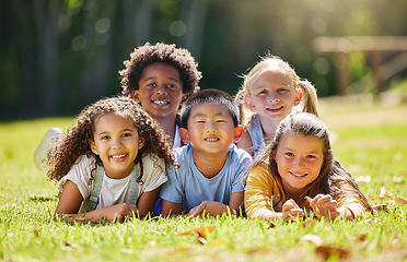 Image showing Portrait, smile and children lying on grass in nature on vacation outdoor for learning. Kids, diversity and happiness of group enjoying summer holiday at park or garden, bonding or relaxing together.