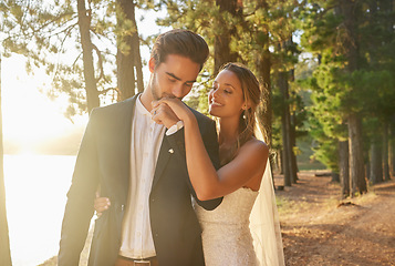 Image showing Kiss, smile and couple at a nature wedding, celebration and marriage ceremony. Happy, affection and a man and woman kissing hand for loyalty, commitment and love at an event in a forest or woods