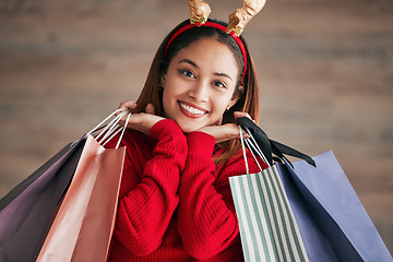 Image showing Portrait, christmas headband and female with shopping bags for a festive or holiday celebration. Happy, smile and face of a woman model with gifts or presents with xmas reindeer ears for an event.