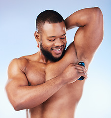 Image showing Deodorant, skincare and black man for beauty, grooming and body hygiene on blue background. Wellness, health and male smile with antiperspirant, fragrance and scent product for underarm in studio