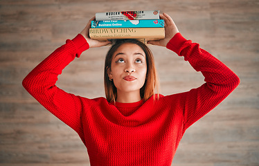 Image showing Reading, student and woman with books on her head while studying in college for a test or exam. Thinking, thoughtful and young female with stories, novels or fiction standing by a wall in the library