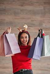 Image showing Shopping bags, happy and female with a christmas headband for a festive or holiday celebration. Happiness, smile and portrait of a woman model with gifts or presents with xmas reindeer ears for event