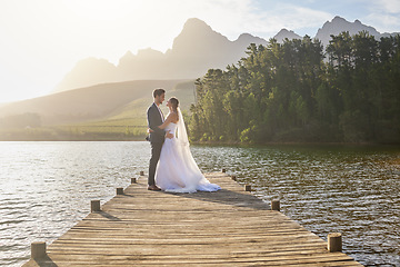 Image showing Married, bride and groom on a pier over a lake in nature with a forest in the background after their ceremony. Wedding, love and water with a young couple in celebration of their marriage outdoor