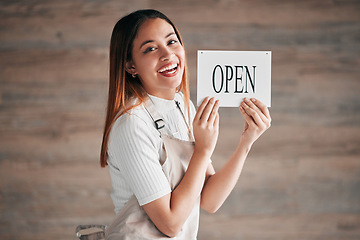 Image showing Coffee shop, portrait and woman holding an open sign in studio on a blurred background for hospitality. Cafe, startup and management with a female owner or entrepreneur indoor to display advertising