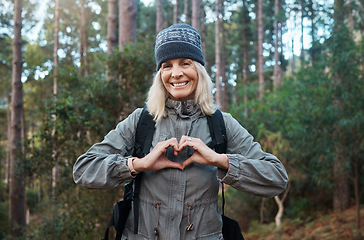 Image showing Portrait, heart and happy woman in forest hiking, fitness and health support, self care hands and cardiovascular workout. Nature, travel or trekking of mature person in woods with love sign or emoji