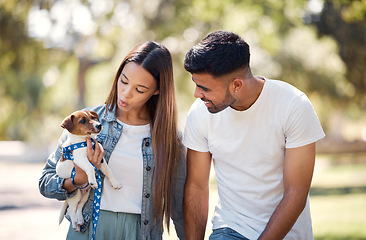 Image showing Couple, holding puppy and walking in park for sunshine, summer or care for happiness, talk and bond. Man, woman and carrying small dog pet with smile, love and family in nature together for wellness
