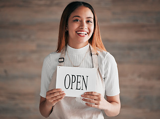 Image showing Coffee shop, portrait and woman holding an open sign in studio on a blurred background for hospitality. Cafe, startup and small business with a female entrepreneur indoor to display advertising