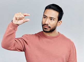 Image showing Little, small sign and hand of man in studio on white background to measure size, scale and height. White background, mockup space and serious male with gesture for review, feedback and tiny symbol