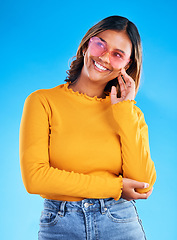 Image showing Fashion, heart sunglasses and thinking happy woman with casual spring clothes, designer brand glasses or outfit style. Gen z aesthetic, trendy idea and young female model on blue background studio