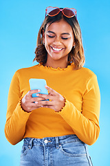 Image showing Woman, phone and smile for social media, communication or chatting isolated against a blue studio background. Happy female smiling with teeth texting on mobile smartphone in happiness for online chat