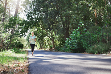 Image showing Fitness, workout and a running senior woman on a road through a forest or park for cardio and endurance. Exercise, mockup and health with a mature female runner or athlete training outdoor in nature